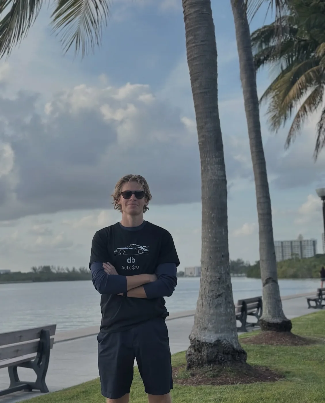Daniil, founder of DB Auto Spa, standing on the Boca Raton waterfront in a DB Auto Spa shirt